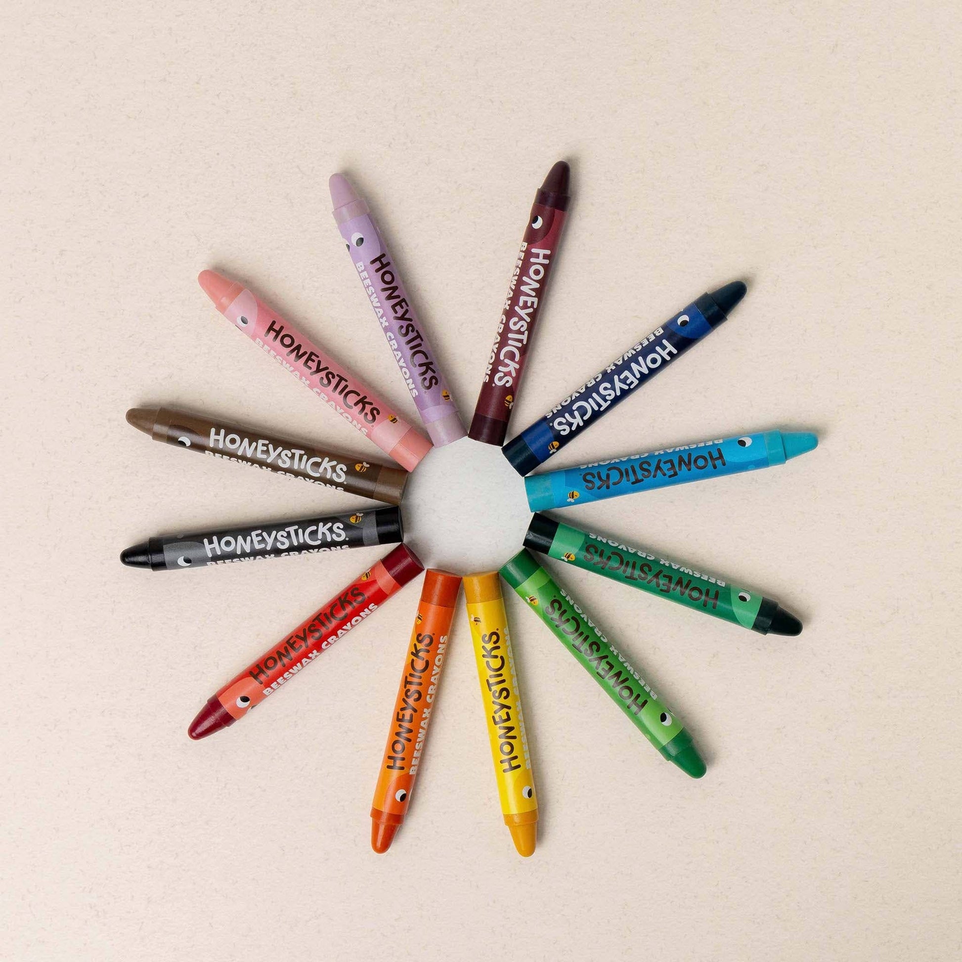 Colorful crayons arranged in a circular pattern on a beige background
