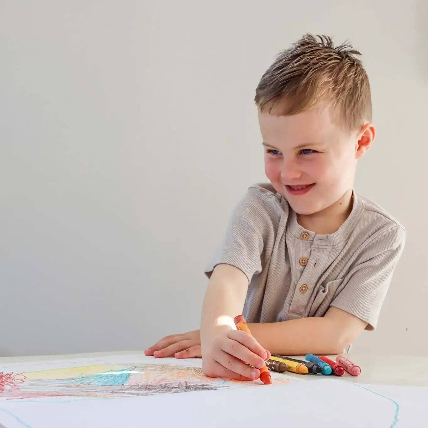 Child drawing with crayons on a white surface