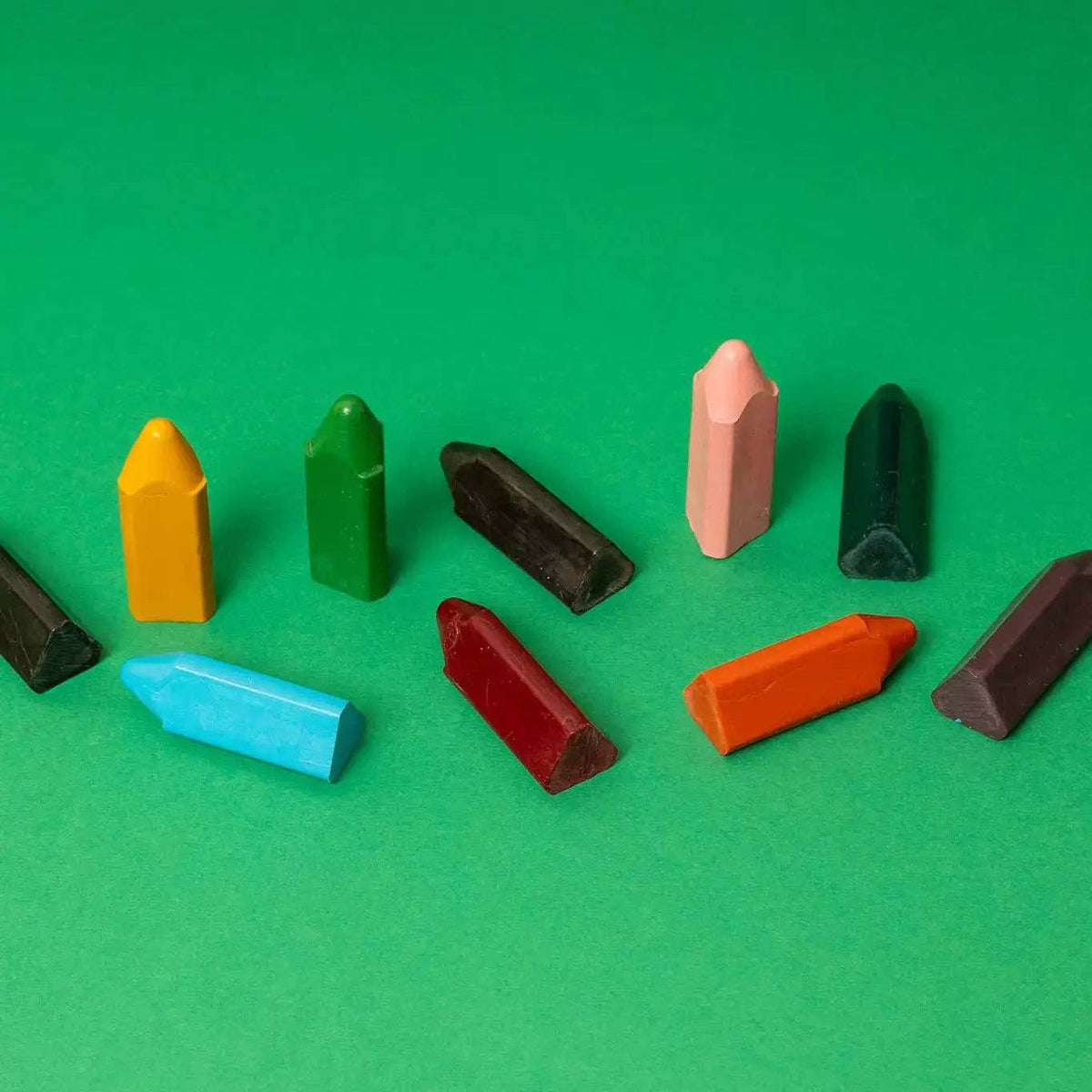Assorted colorful crayons on a green background
