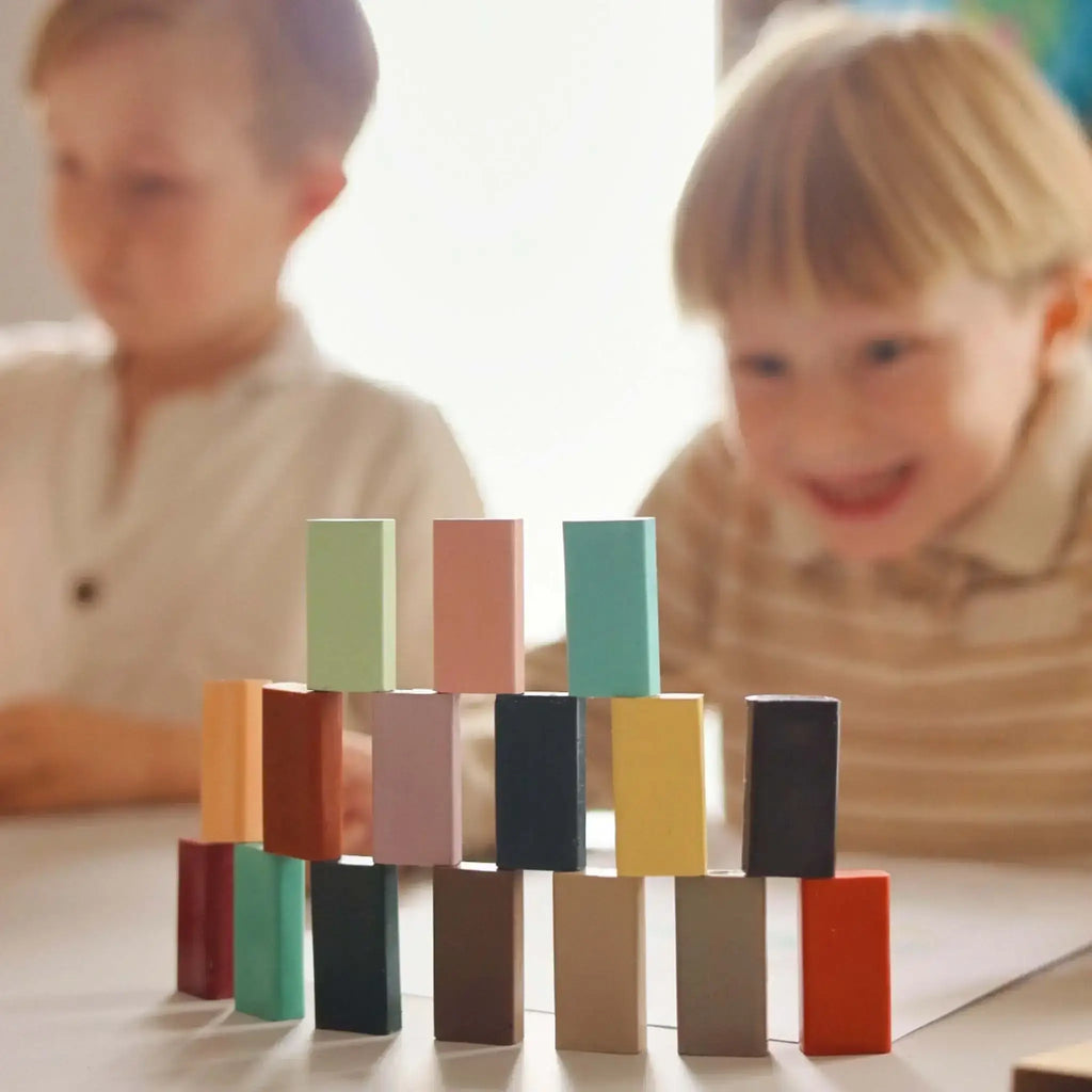 Children playing with colorful crayon blocks on a table.