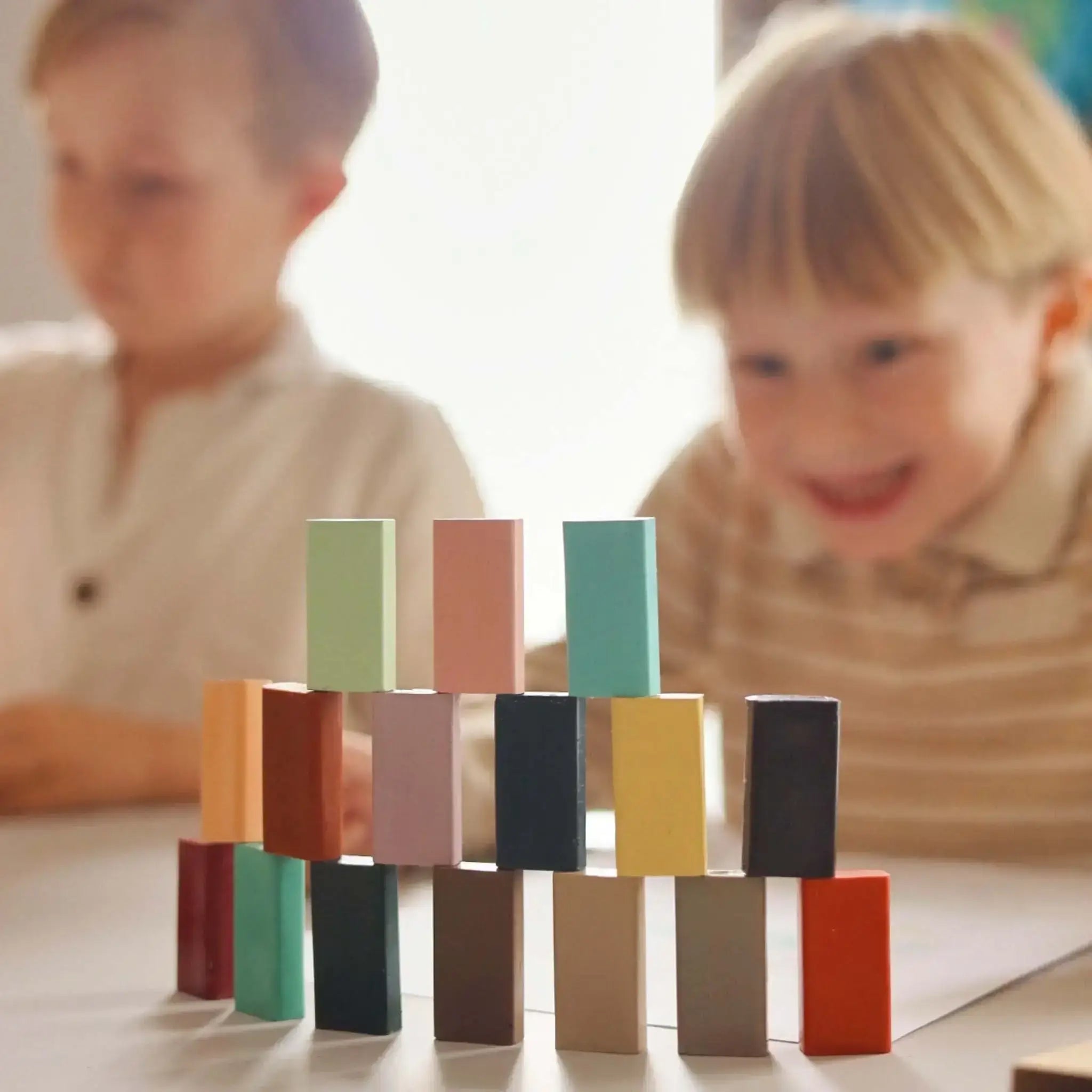 Children playing with colorful crayon blocks on a table.