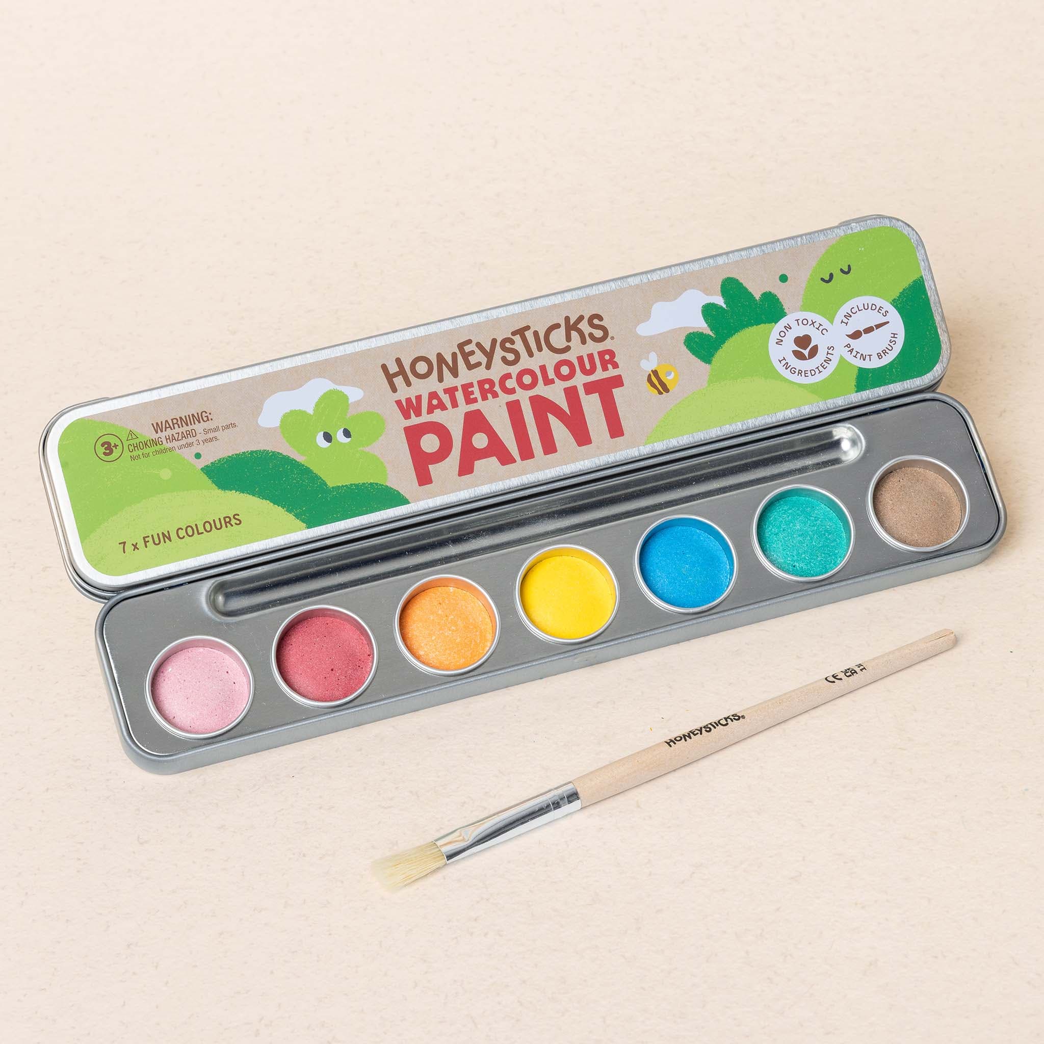 Set of watercolor paint with a brush on a beige background