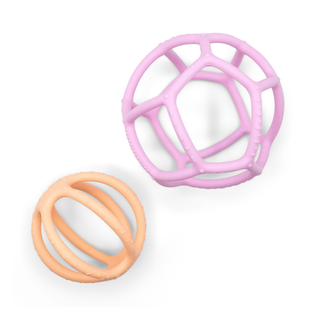 Two silicone sensory balls in pink and peach colours with a geometric open-frame design, intended for babies to chew on.