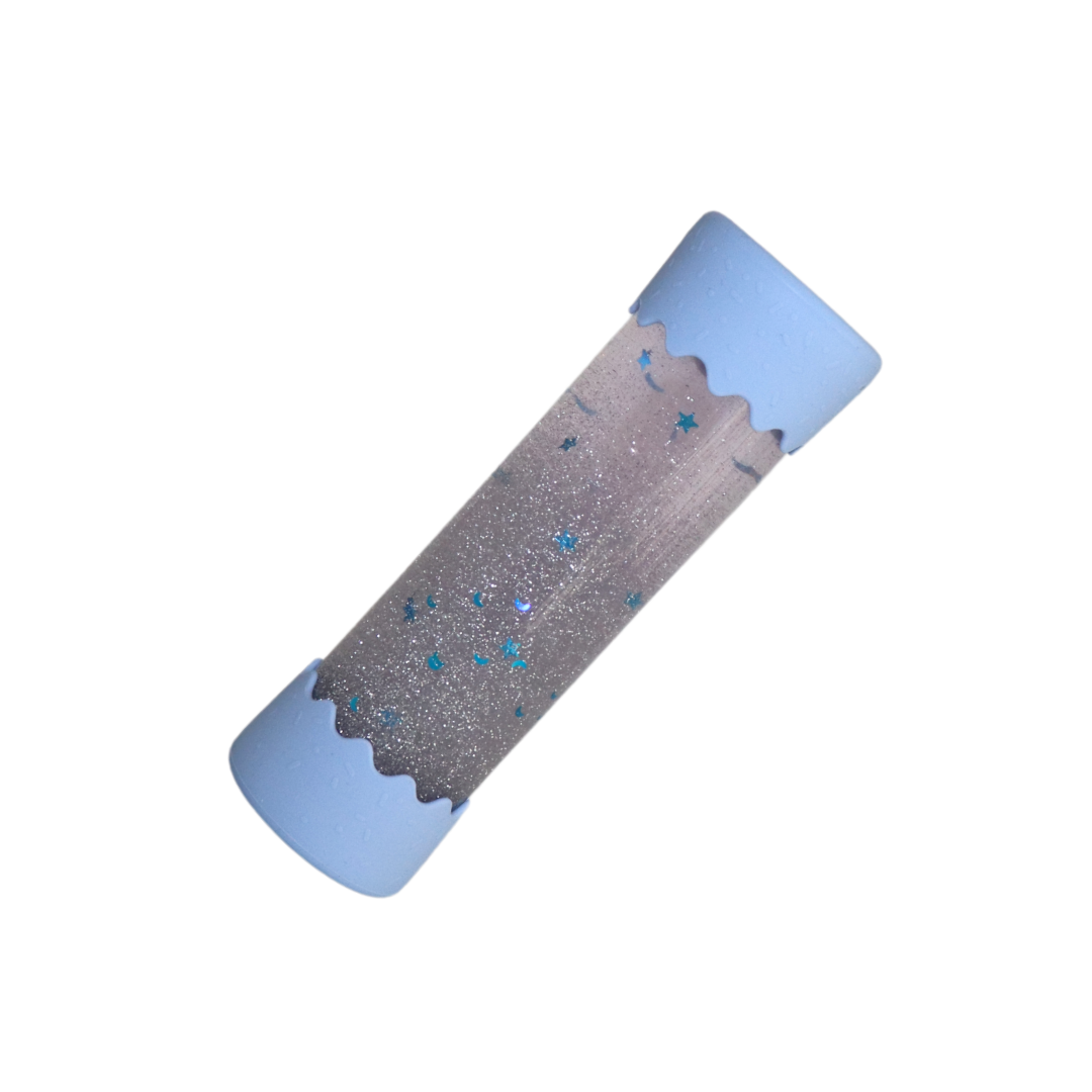A Baby Calm Down Bottle with a transparent body and silver lid, pre-filled with sparkles and water, shown in packaging with a geometric pattern.