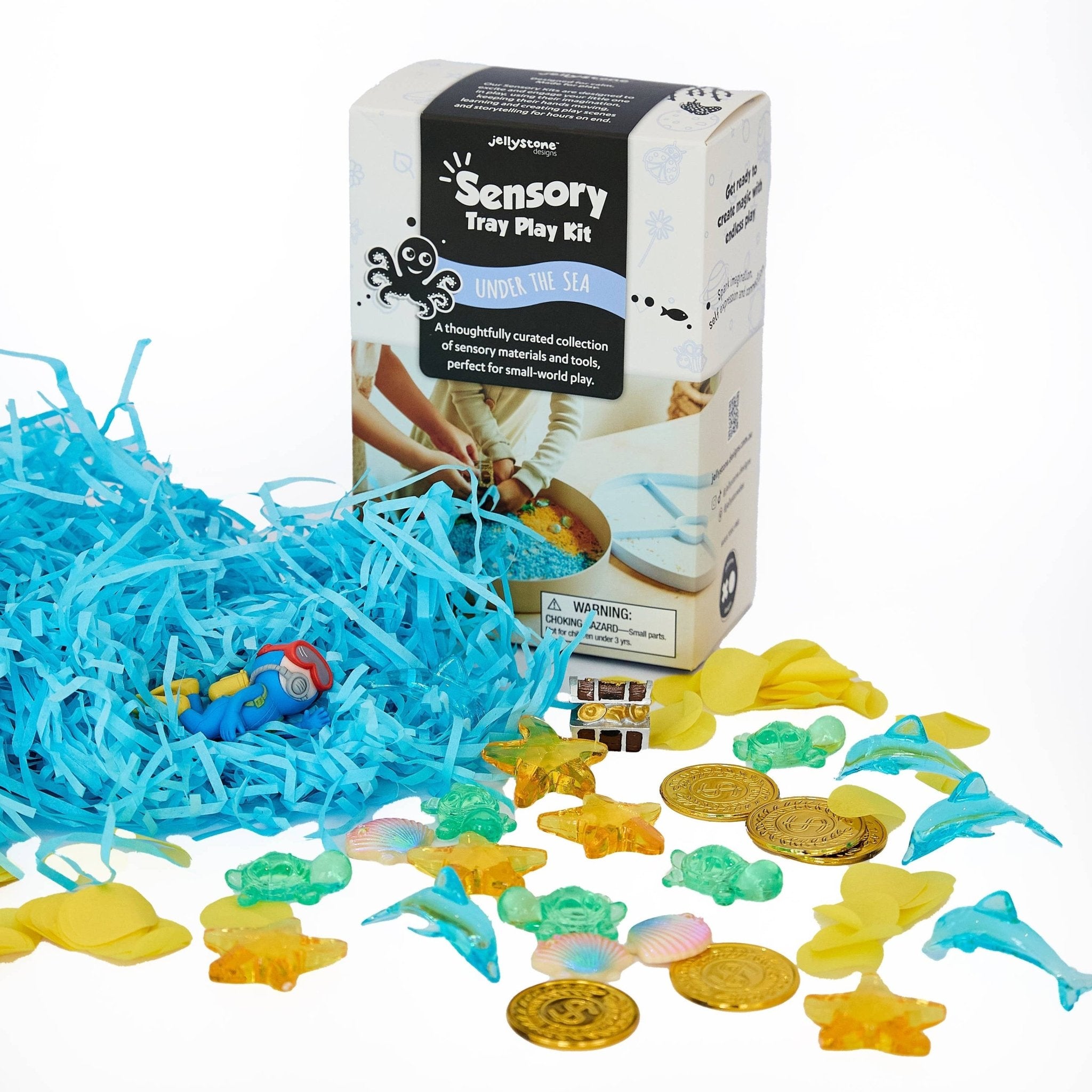 Sensory play kit with blue shredded paper, colorful sea-themed toys, and a box labeled 'Sensory Tray Play Kit' on a white background.