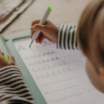 Child practicing letter writing with a green marker