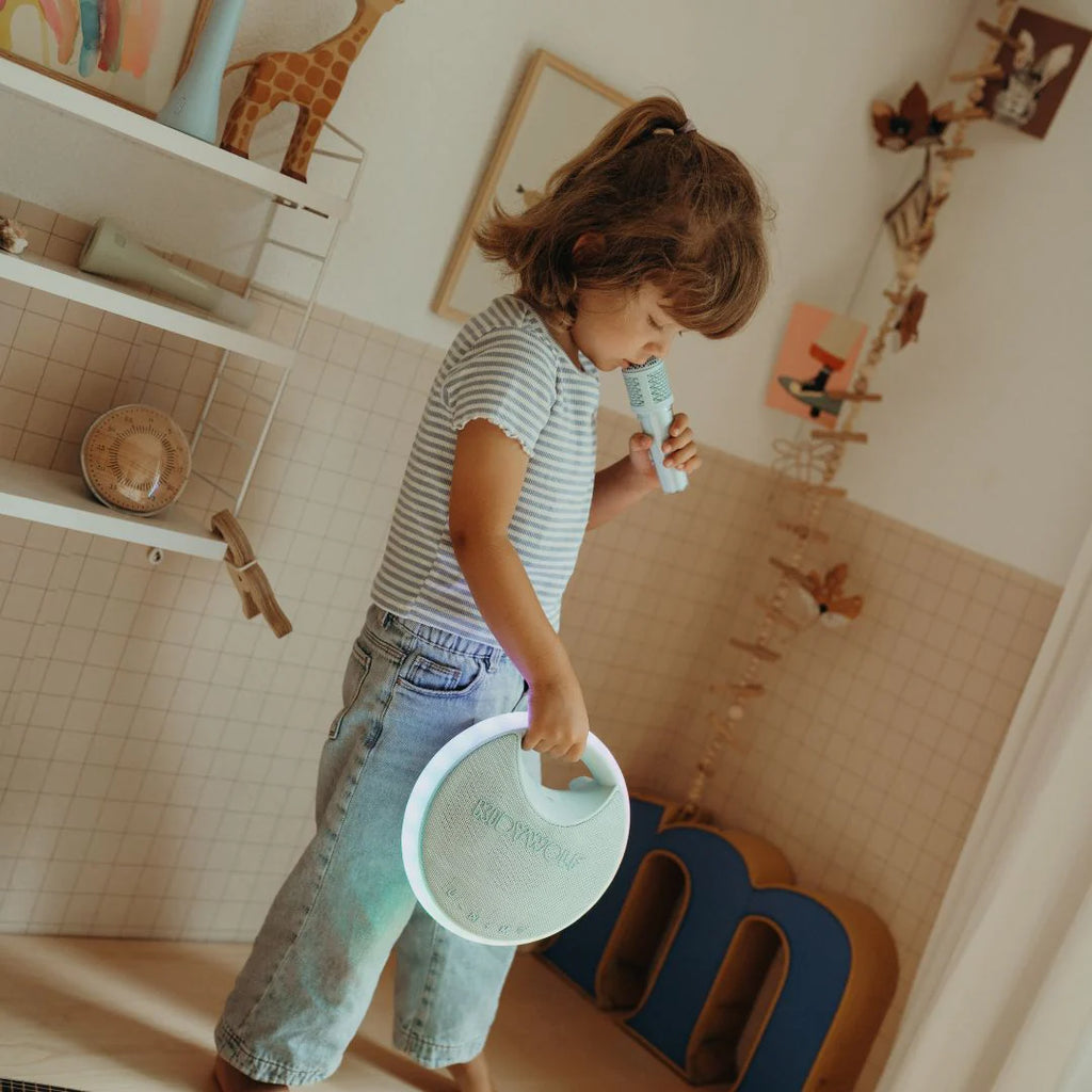Child playing with a microphone and plate in a room with shelves and decor.