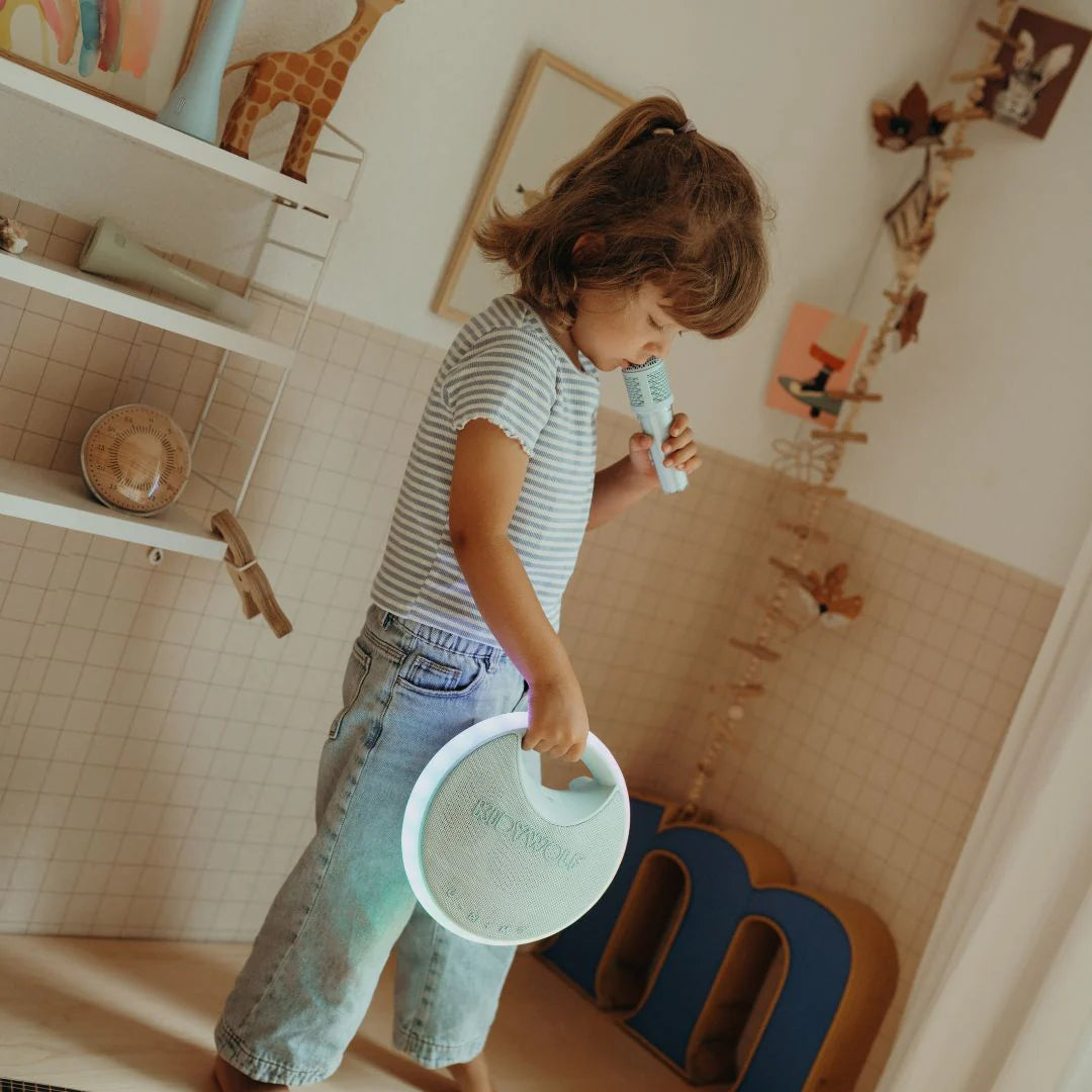 Child playing with a microphone and plate in a room with shelves and decor.