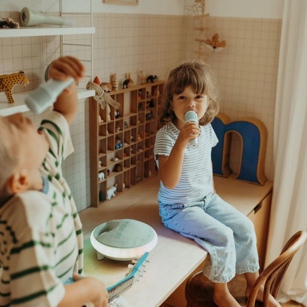 Two children playing with toys in a room with wooden shelves and a beige wall.