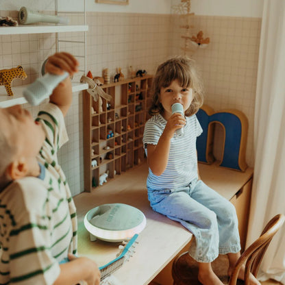 Two children playing with toys in a room with wooden shelves and a beige wall.