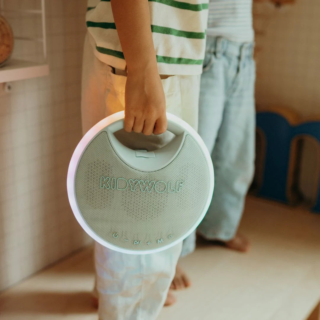 Person holding a green and pink product with 'KIDWOLF' branding in a casual setting.