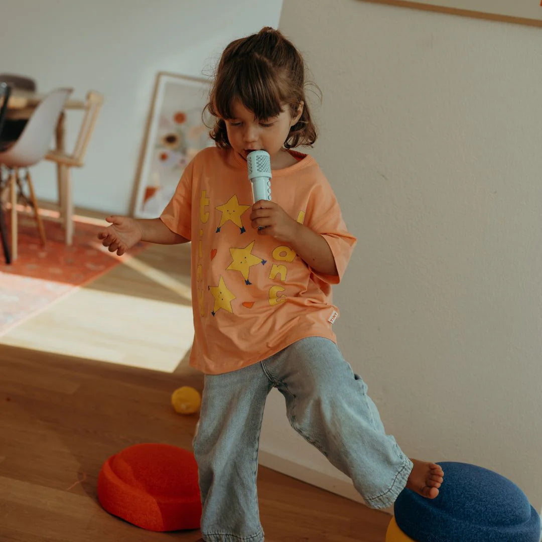 Child holding a microphone in a room with colorful furniture