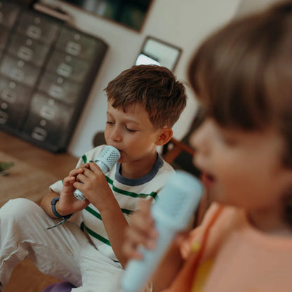 Two children playing with microphones in a room with musical equipment.