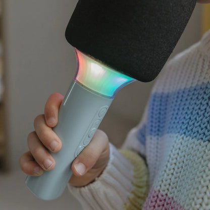 Hand holding a colorful toy microphone with a blurred background