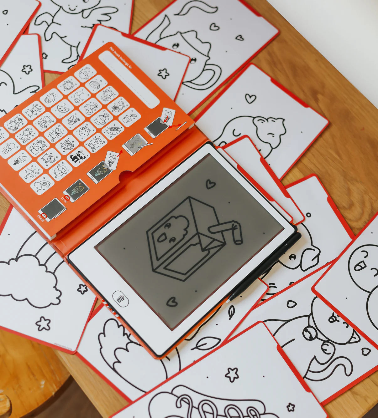 Children's drawing tablet with stamps on a wooden surface with coloring sheets.