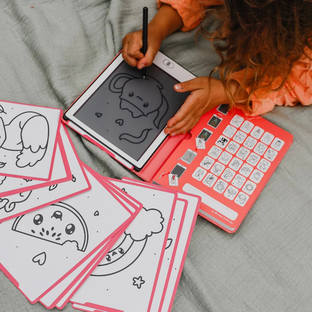 Child using a small electronic device with drawing pad and coloring sheets on a bed