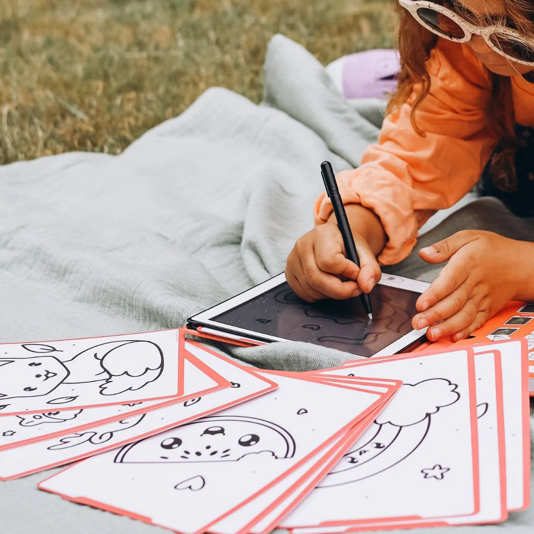 Child coloring on a tablet with coloring sheets outdoors