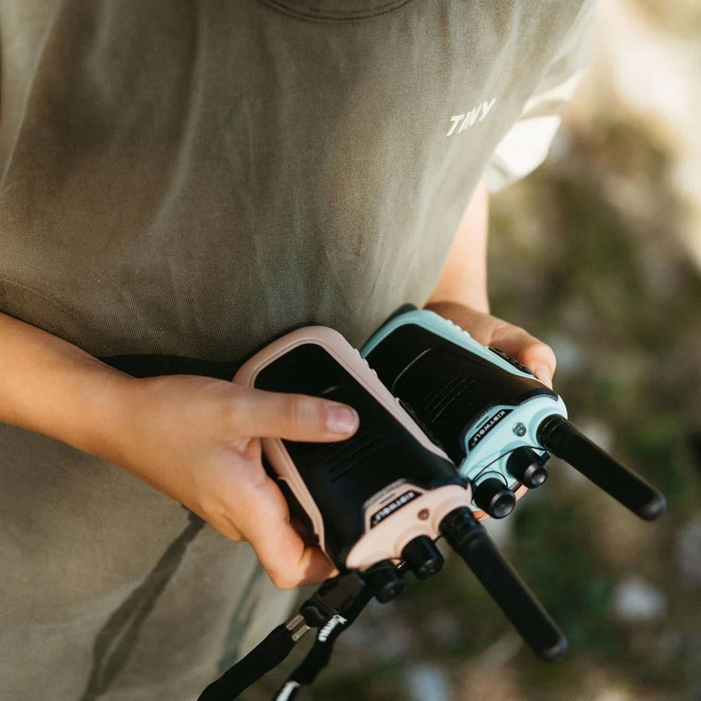 Person holding a walkie-talkie with a blurred natural background