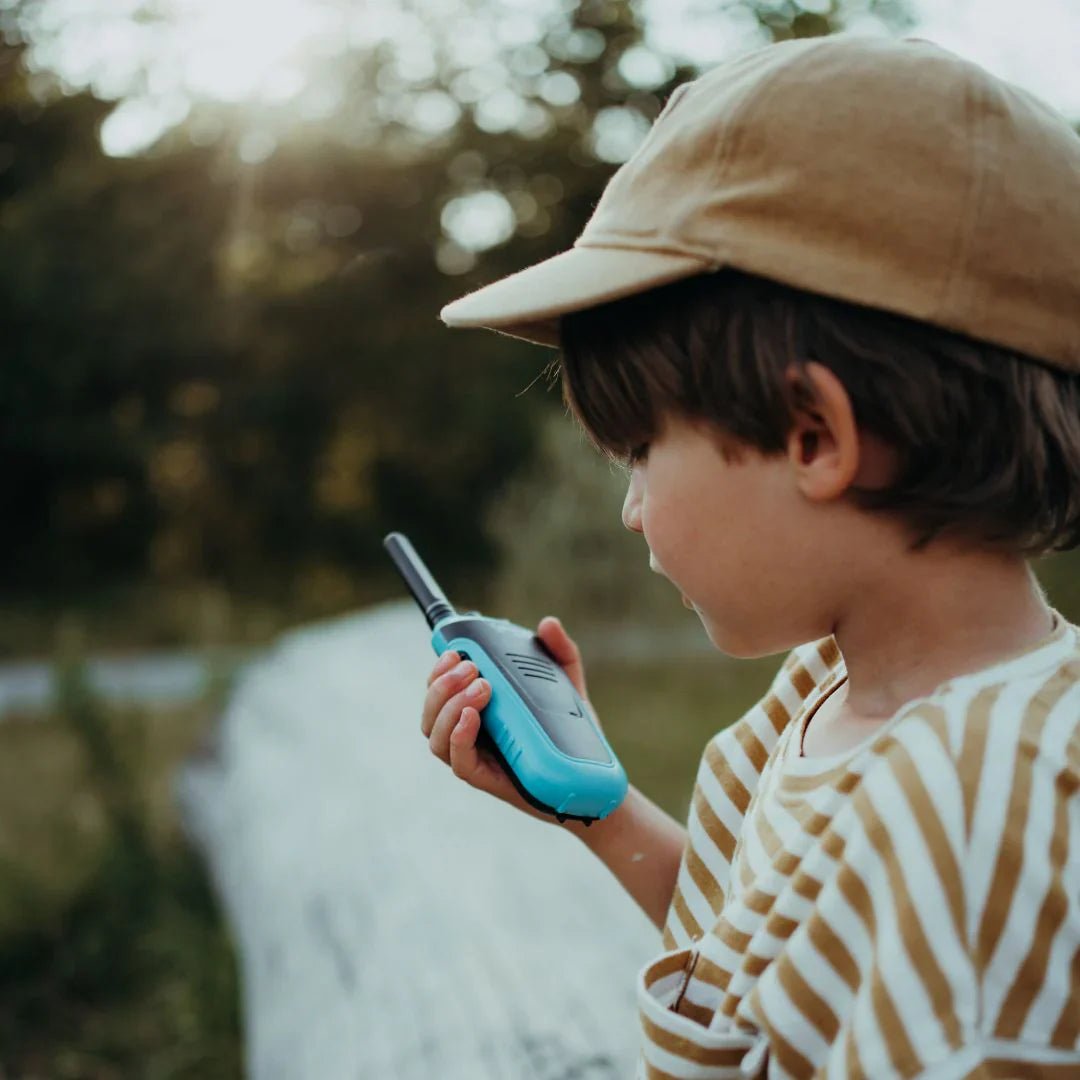 Child holding a walkie-talkie outdoors with a natural background