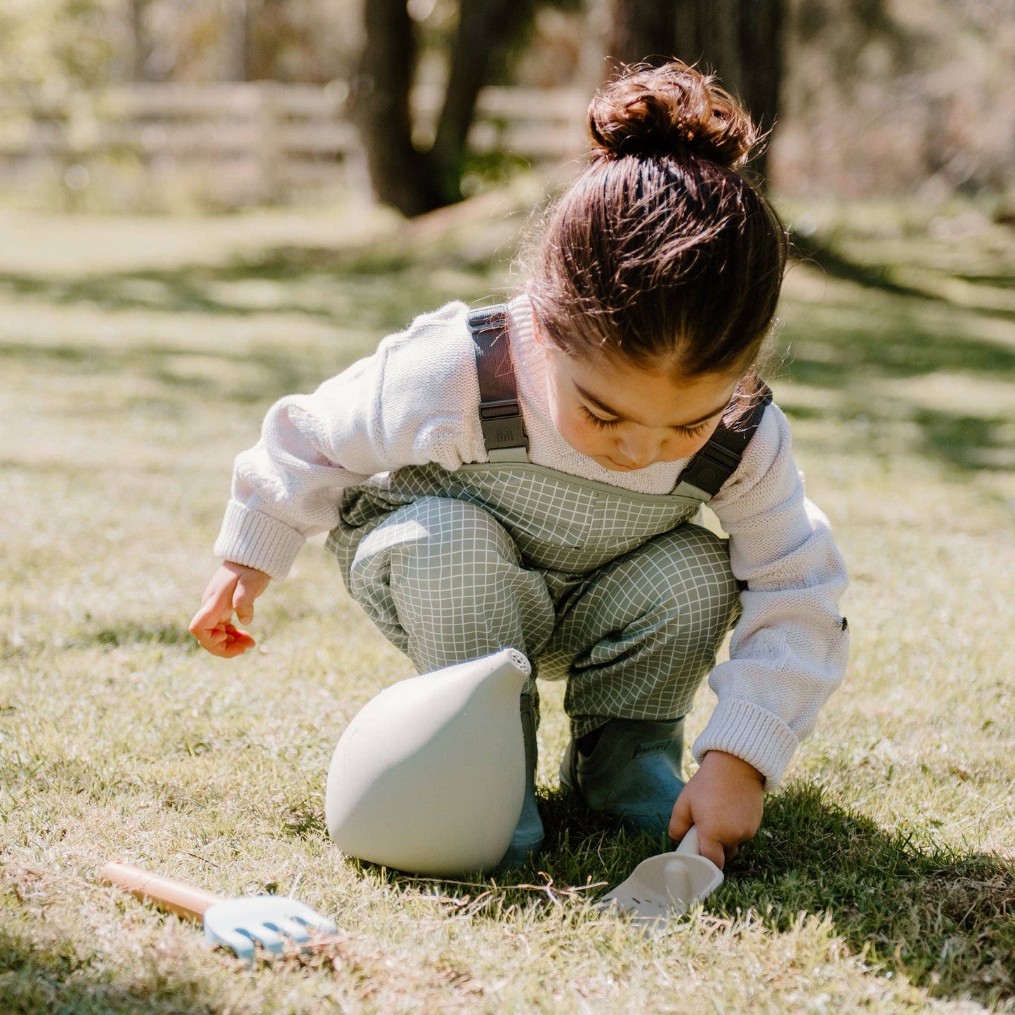 A set of silicone gardening tools including a watering can, a fork, and a trowel, in soft pastel colors.
