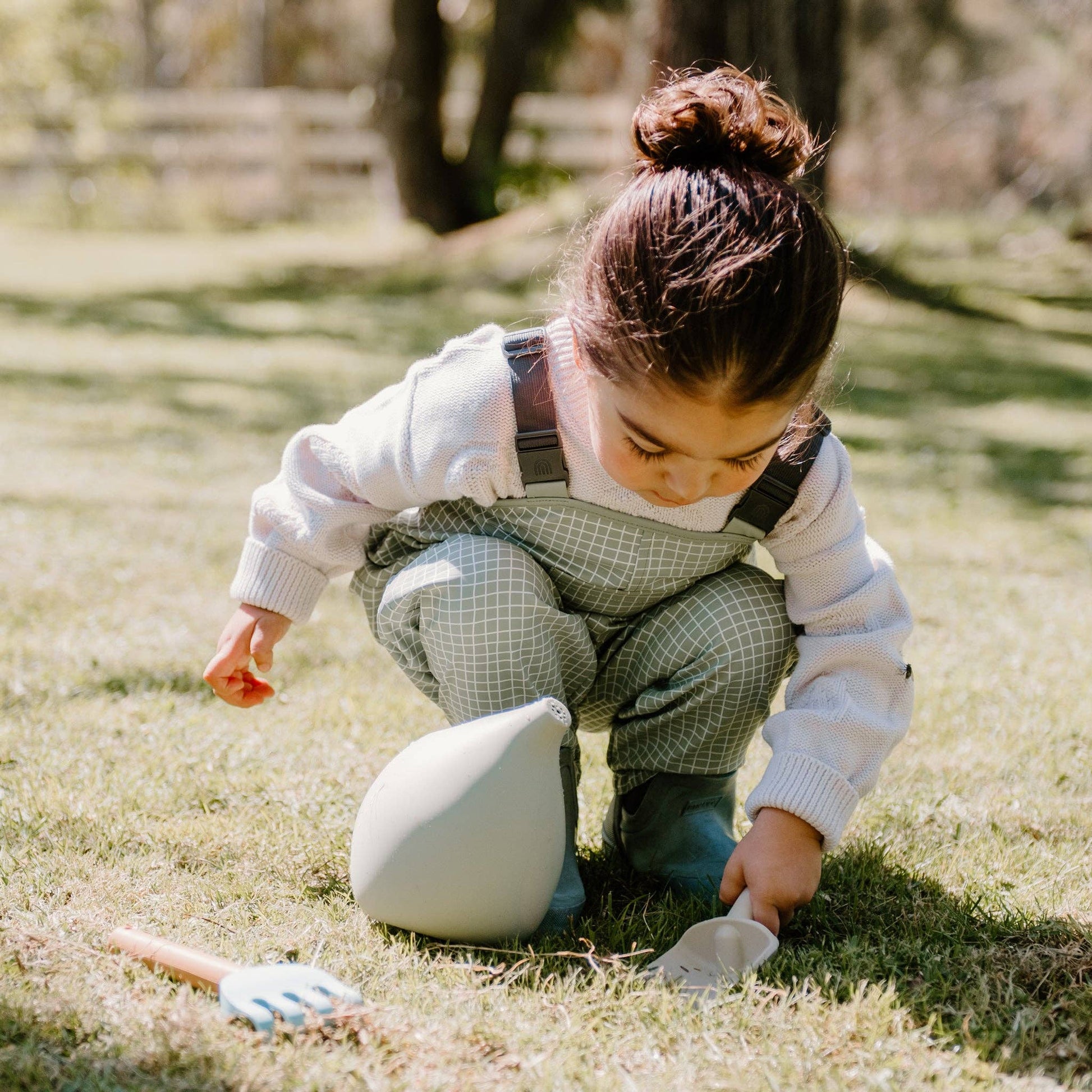 A set of silicone gardening tools including a watering can, a fork, and a trowel, in soft pastel colors.