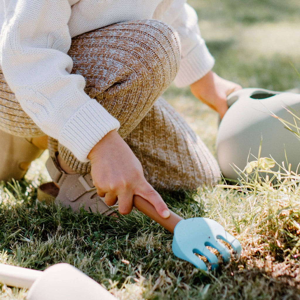 Child holding rake in grass