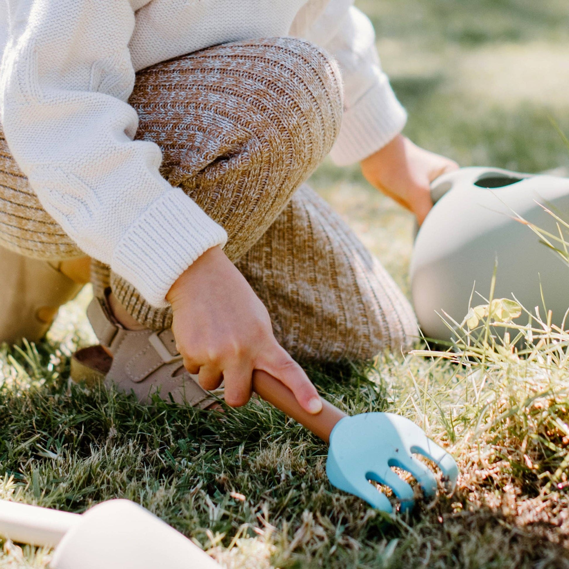 Child holding rake in grass