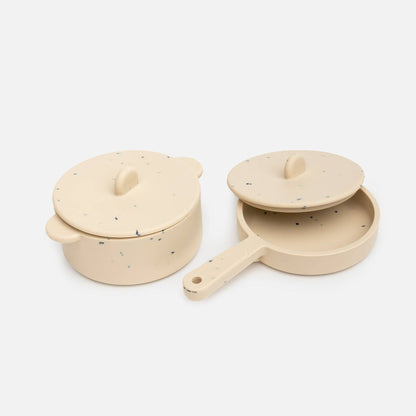 Beige silicone toy pot and pan with lids on white background.