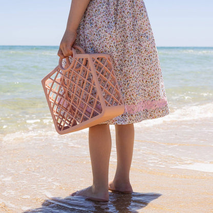 Child at the beach holding pink silicone bag