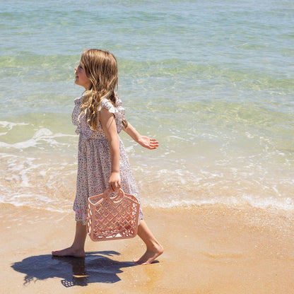 Child at the beach holding pink silicone bag