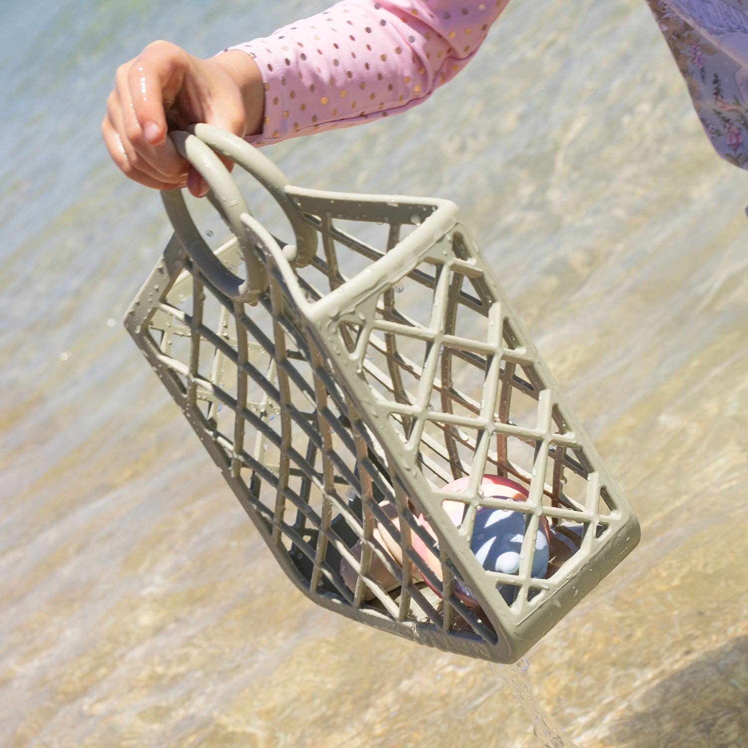 Child holding Kynd Baby - Silicone Bag - Sage at the beach