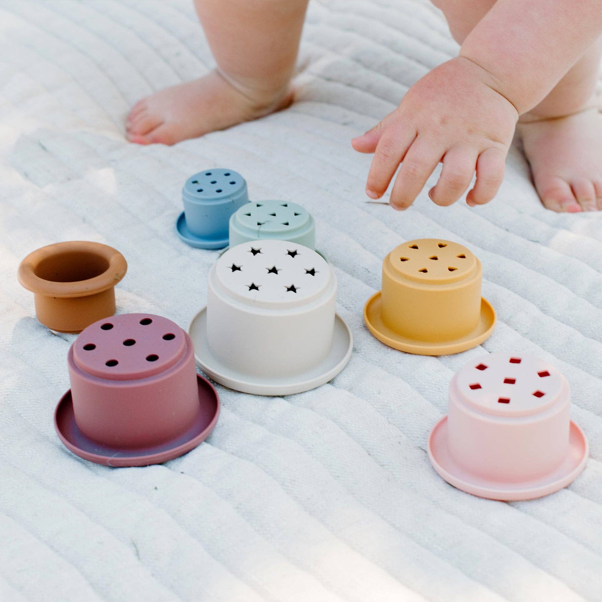 Child playing with silicone stacking cups with various shape cutouts