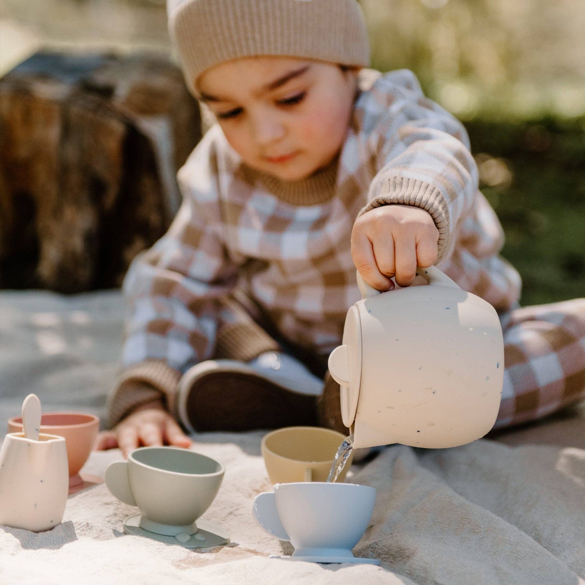 Child soaring water from teapot into teacup.