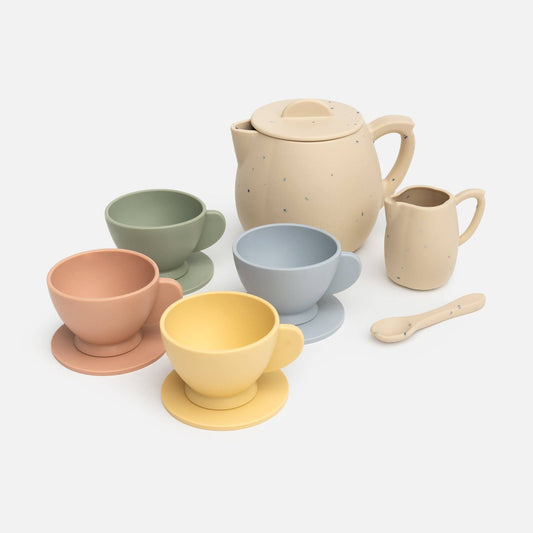 A silicone tea party set including a teapot, cups, saucers, and a spoon, in various soft colors like beige, green, blue, pink, and yellow.
