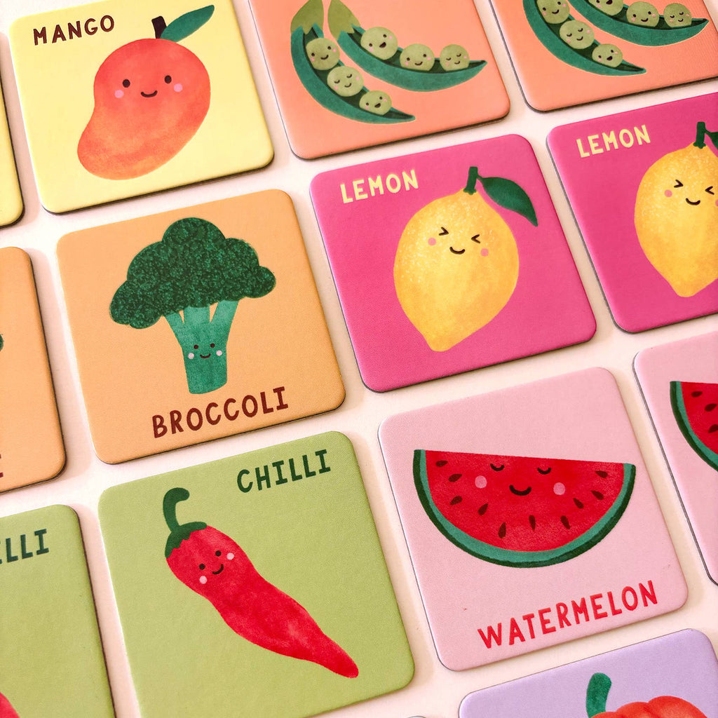 Set of colorful coasters with illustrations of fruits and vegetables on a light pink background.