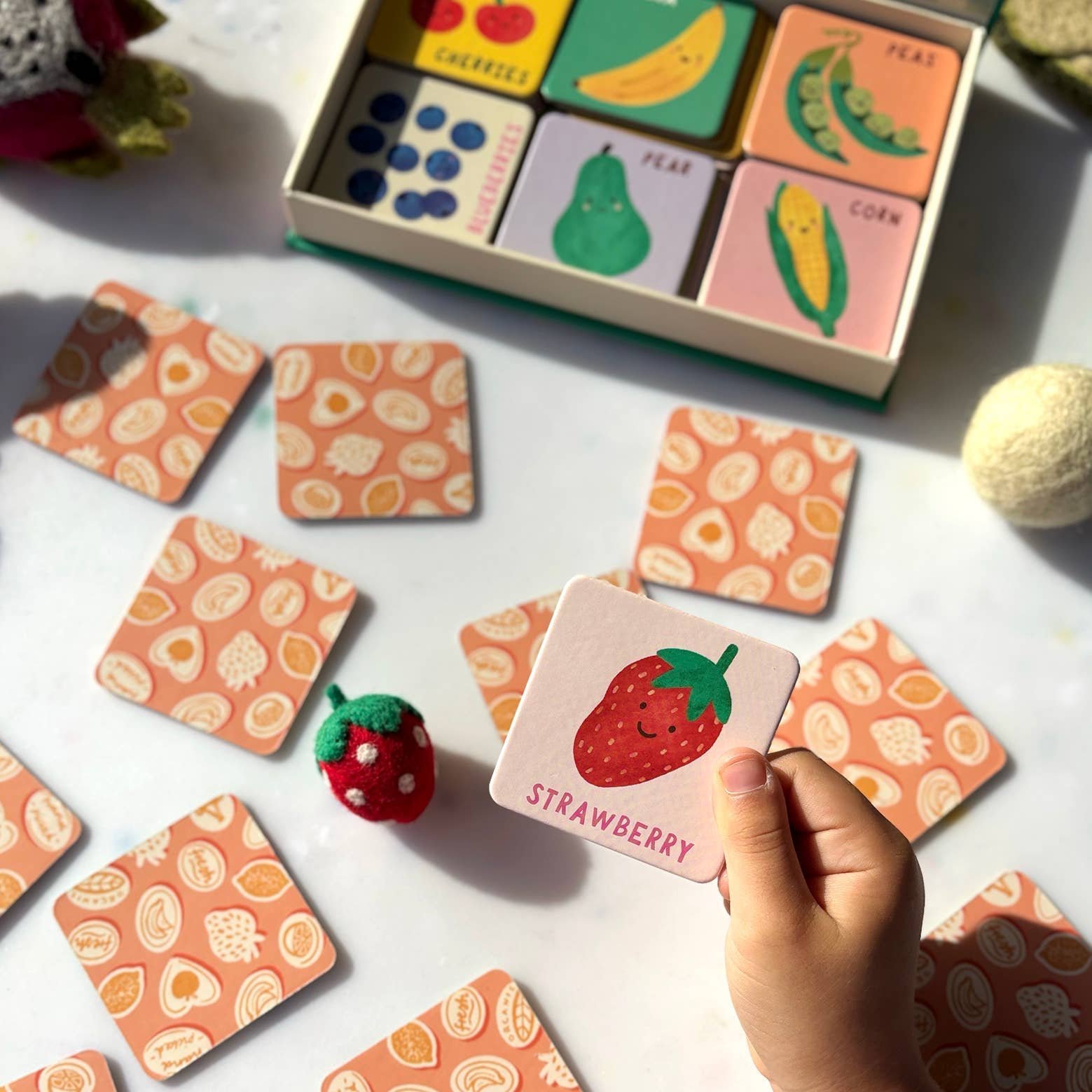 Children's educational toy with fruit-themed cards on a white surface.