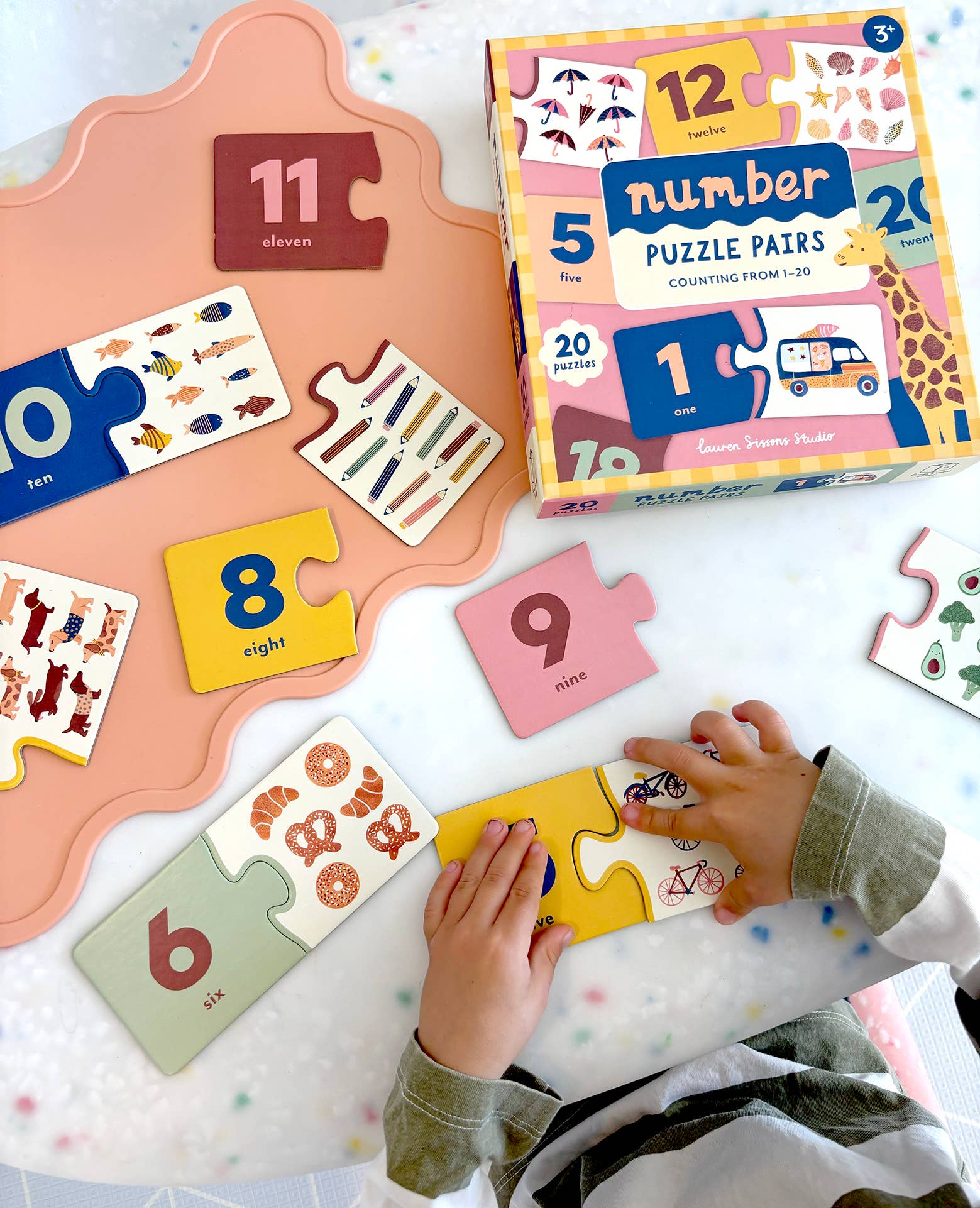 Children's number puzzle pairs on a colorful surface with a child playing with the puzzles.