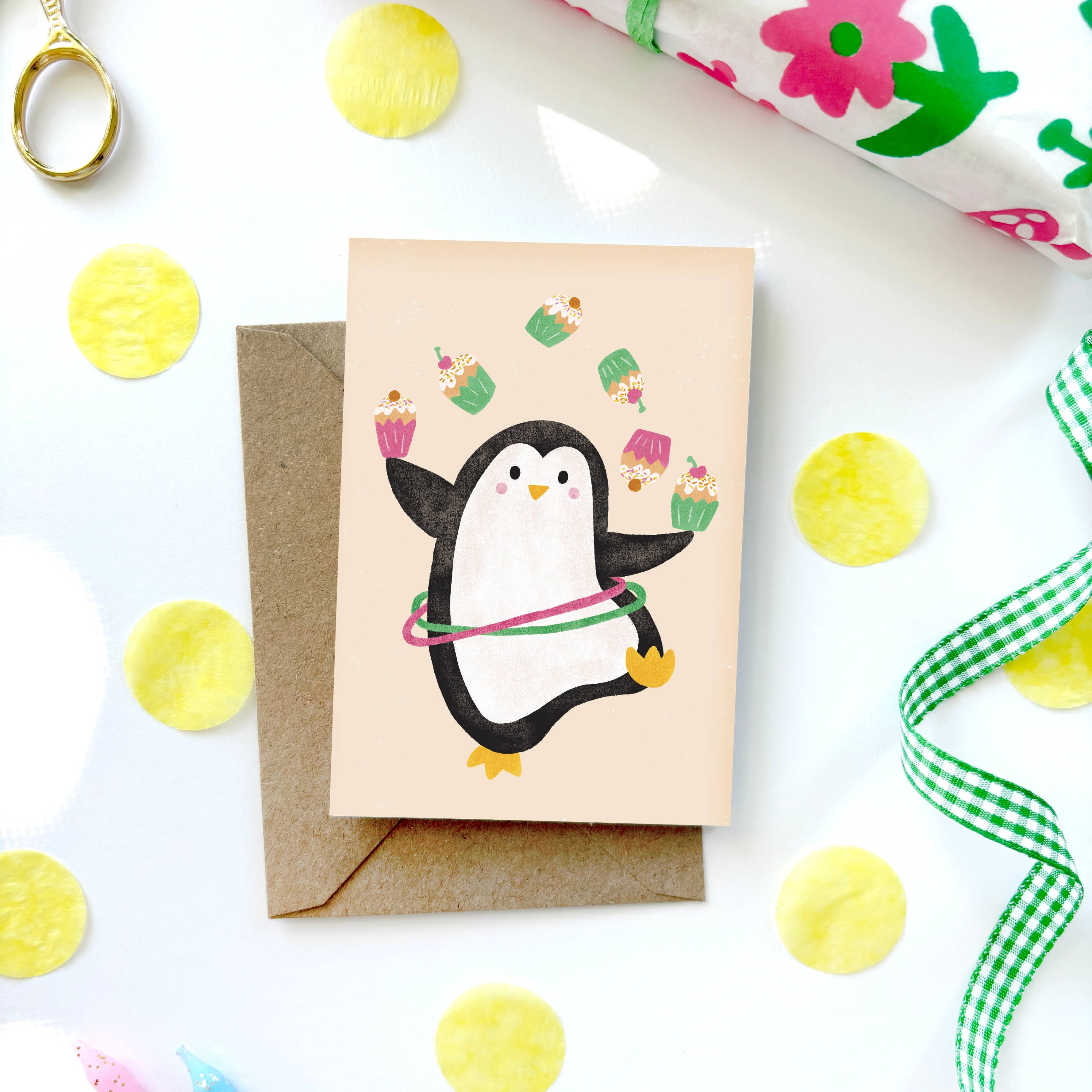 Greeting card with a penguin design on a white surface with decorative items.