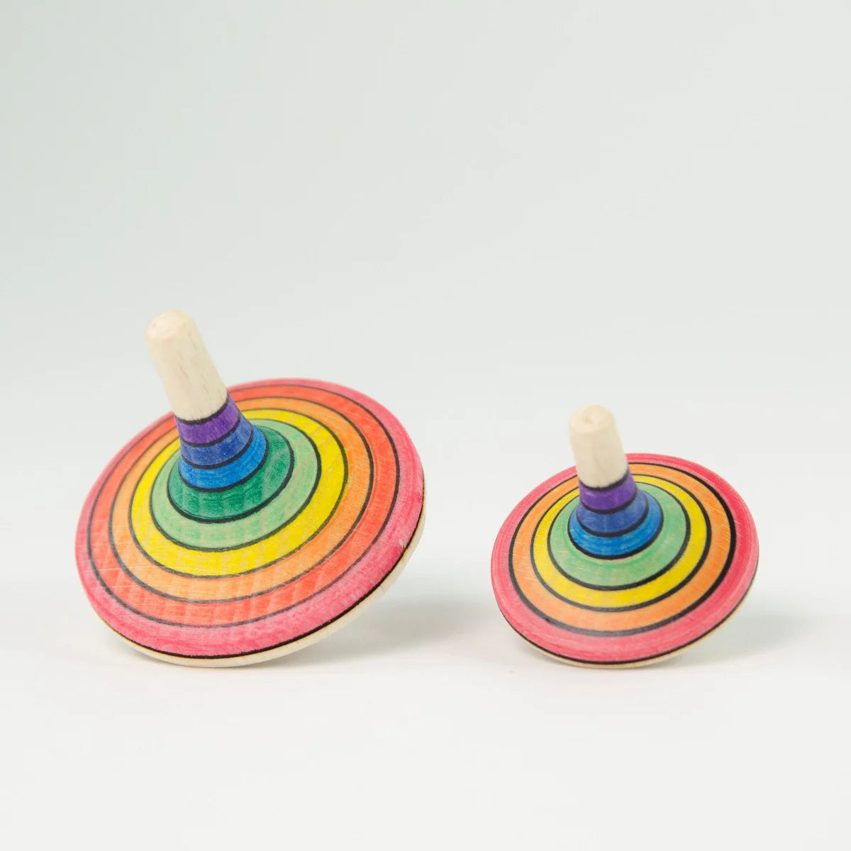 Two rainbow-colored wooden spinning tops on a white background