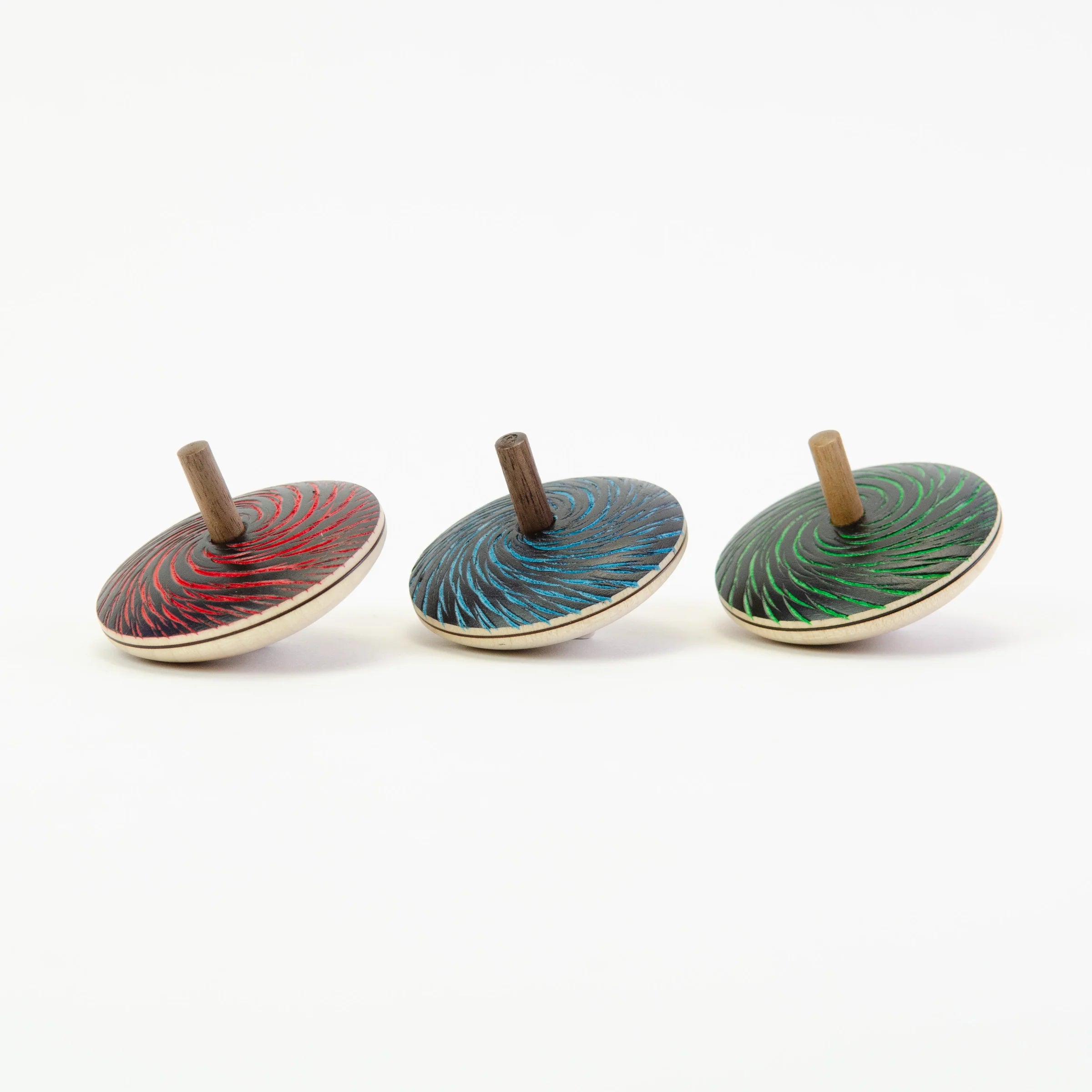 Three wooden top toys with colorful designs on a white background