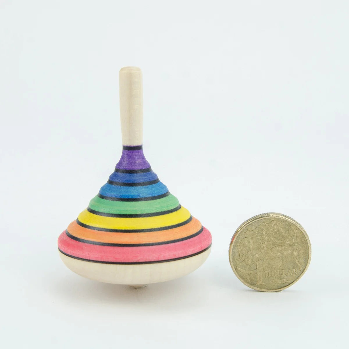Colorful striped wooden top next to a coin on a white background