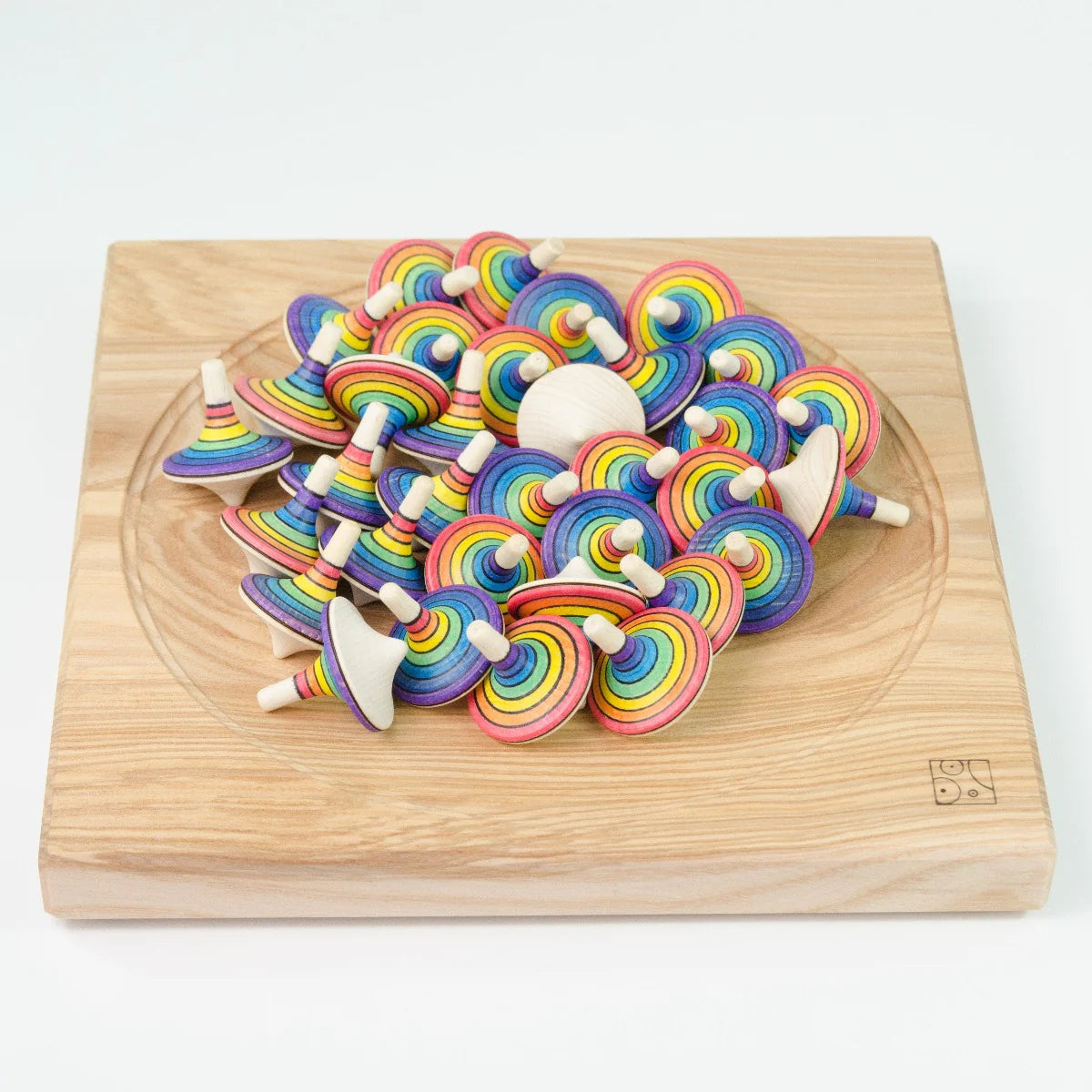 Colorful wooden spinning tops on a wooden board with a white background