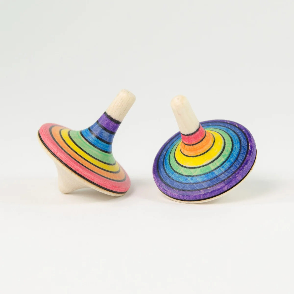 Two rainbow-colored wooden spin tops on a white background