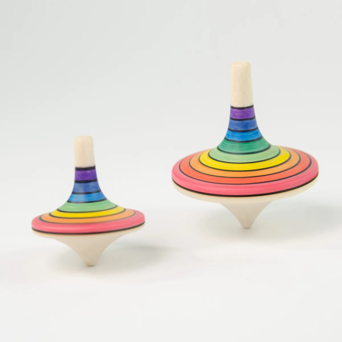 Two rainbow-colored wooden spinning tops on a white background