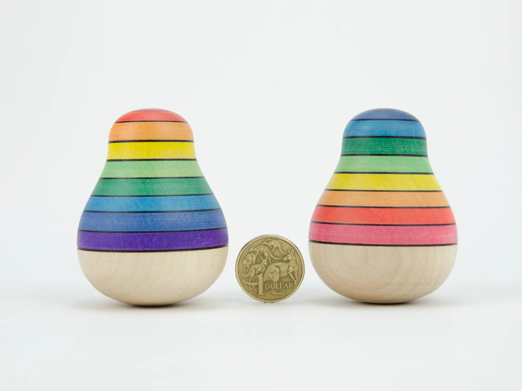 Two rainbow-colored wooden toys next to a gold coin on a white background