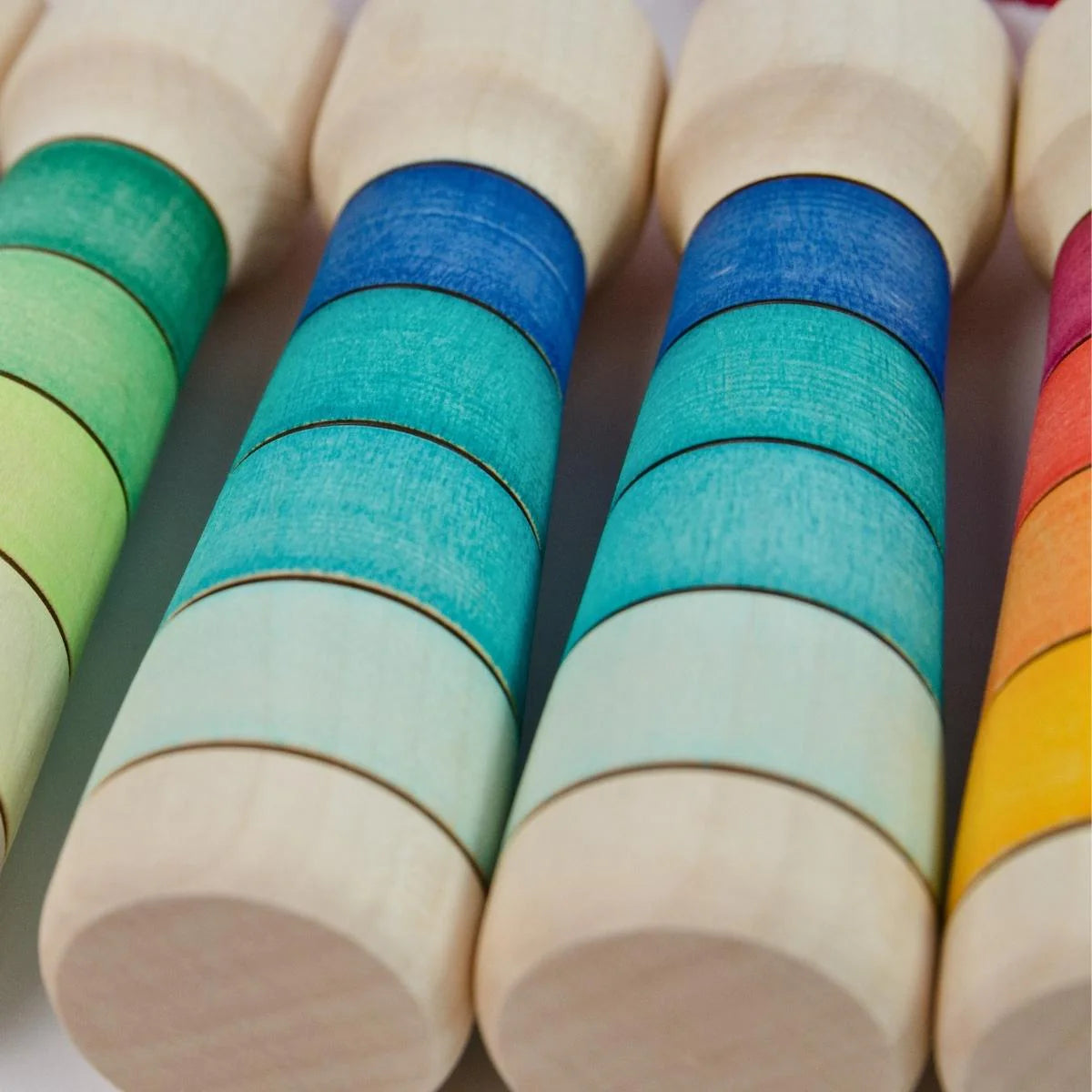 Colorful wooden cylindrical blocks with gradient colors on a white background