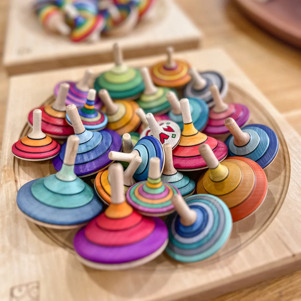 Colorful wooden spinning tops on a wooden tray