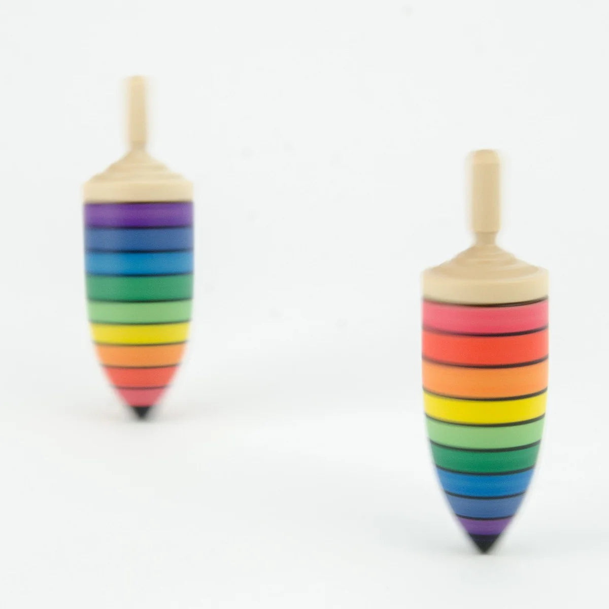 Two rainbow-striped wooden spin tops on a white background