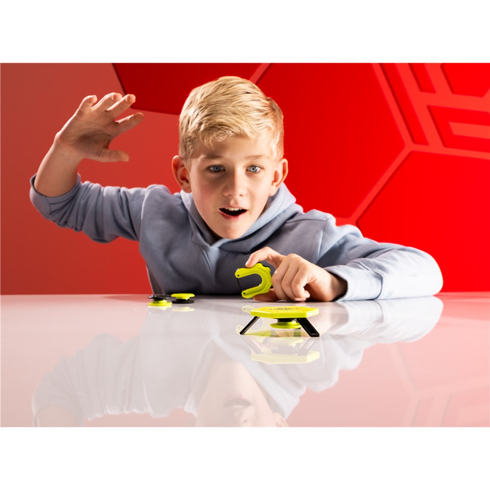 Child playing with toy cars on a reflective surface with a red geometric background