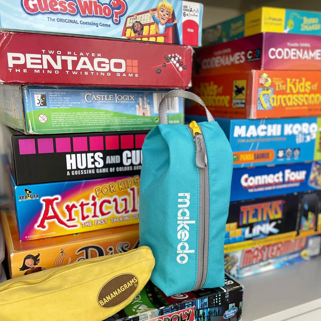 Stack of board game boxes with a blue Makedo bag in the foreground